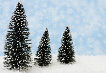 Three evergreen trees on snow with snowflake background