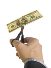 A hand cutting a dollar bill with a pair of scissors.