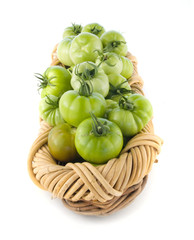Green tomatoes in a basket isolated on white background.