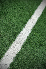 Fototapeta premium White line painted on green grass. Soccer field shot.