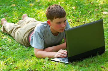 teenager with laptop on grass