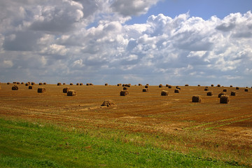 Haystacks on a background of the blue sky with clouds.