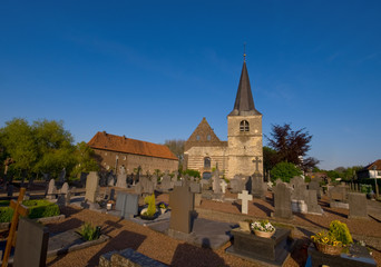 Fototapeta na wymiar Cmentarz w słoneczny dzień i błękitne niebo z średniowiecznego kościoła