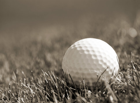 Sepia toned close-up of golf ball in grass