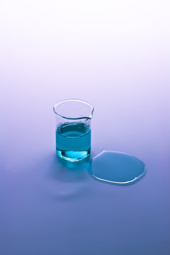 Test tube and spilled liquid with blue and purple background