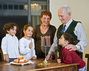 grandperents and grandchildren lightening Hanukkiyah together