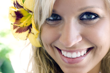 Close-up photo of blonde white woman with flower in hair..