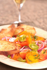 Plate of Colorful Tomato Salad With a Glass on Wine and Bread