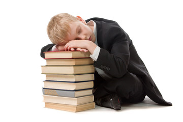 The schoolboy has fallen asleep on a pile of books.