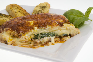 Lasagna and garlic bread against white