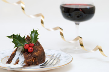 Christmas pudding slice with brandy sauce and glass of wine