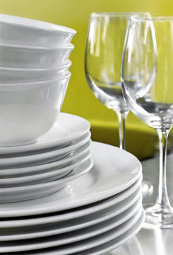 Stack of Commercial White Plates Bowls and Wine Glasses