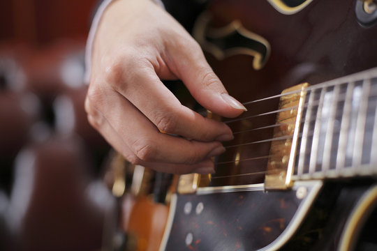 A Hand poicking on guitar strings