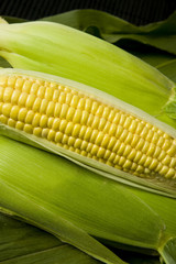 Sweetcorn cob, with sealed cobs and corn leaf background.