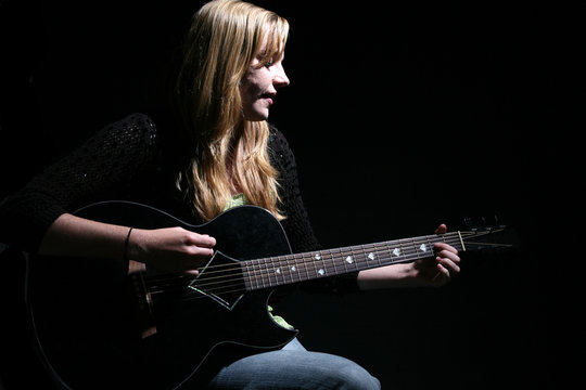 woman with long hair playing guitar and singing