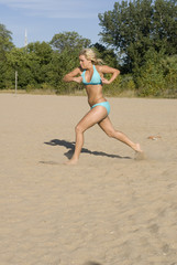 Funny photo of a blonde female in a bikini running in the sand