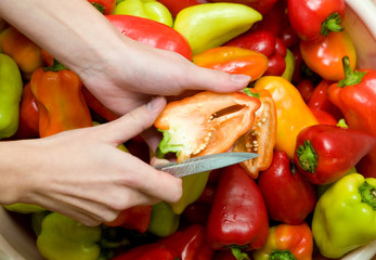 many colored sweet peppers with hands and knife