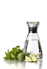 Jug of cold water with lemon balm and lime isolated