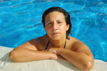 Mujer descansando en el bordillo de la piscina - obrazy, fototapety, plakaty