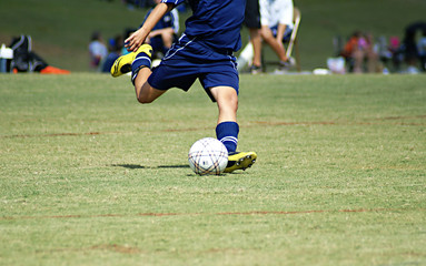Young boy strking a soccer ball in a game.