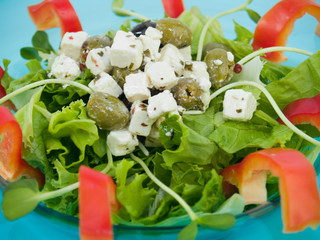 Salad with feta cheese and olives on a teal glass plate