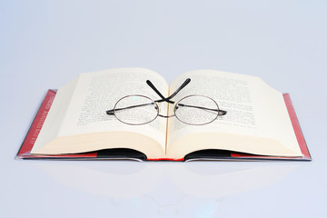 open book with a pair of eye glasses on top.
