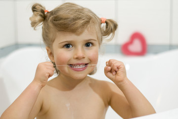 Cute girl cleaning teeth by dental floss