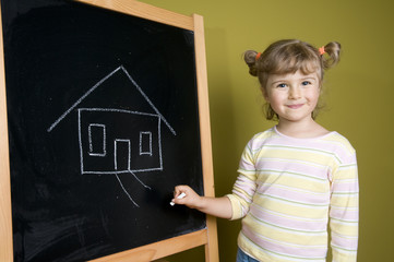 Little girl drawing house on blackboard