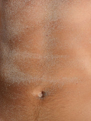 Naklejka premium A tanned belly covered in white sand