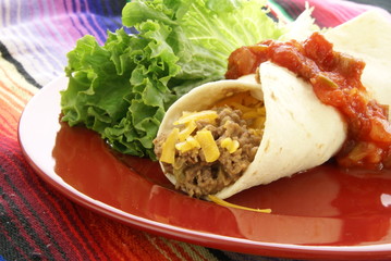 Mexican burrito with beef beans cheese and salsa on red plate
