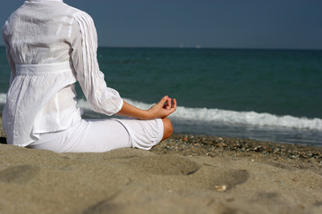 A woman is meditating by the sea