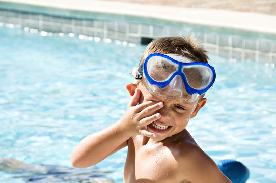 Young boy rubbing his eyes wearing goggles