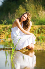 Young romantic woman on a river bank.