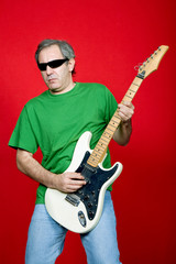 mature casual man plauing guitar on a red background