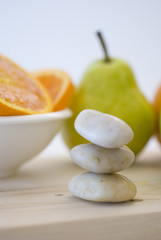 zen stones and orange, apple, pear fruits on background