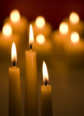 Three candles with glowing candles in background