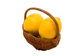 Two fresh yellow lemons in small wicker basket