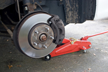 The rim a car is removed showing the front rotor and caliper.
