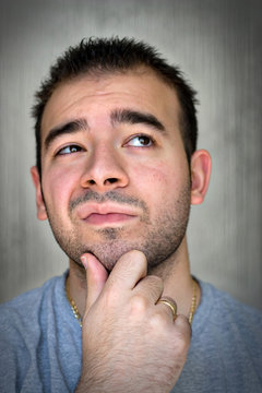 A Young Man With His Hand On His Chin Thinking.