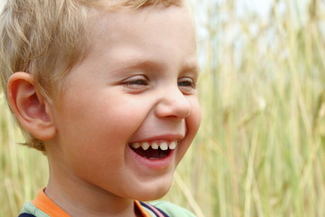 3 years old boy laughting on a wheat field