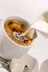 Puring milk in a cup of coffee