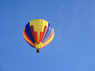 Multicoloured hot air balloon up in the blue sky.