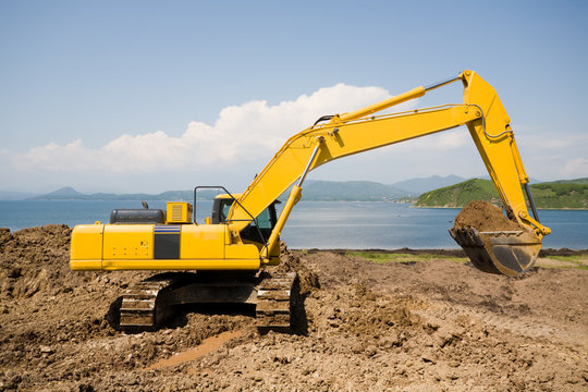 Excavator on the workplace on a background of the sea.
