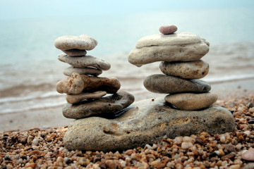 double balanced pyramids against each other on sea shore