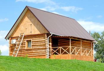Obraz premium The wooden house with a lawn on a background of the blue sky