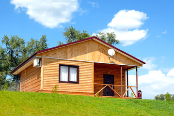 Fototapeta na wymiar Drewniany dom z trawnikiem na tle błękitnego nieba