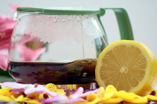 teiera con fetta di limone e fiori giali e rosa