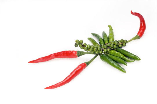 Chili and black pepper lying on white surface scorpion shaped