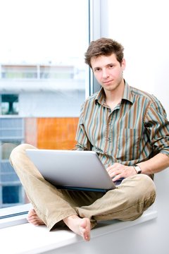 Businessman sitting in office window and working on laptop