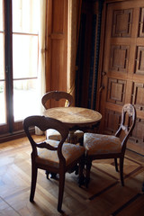 interior with wooden round table and three chairs against window